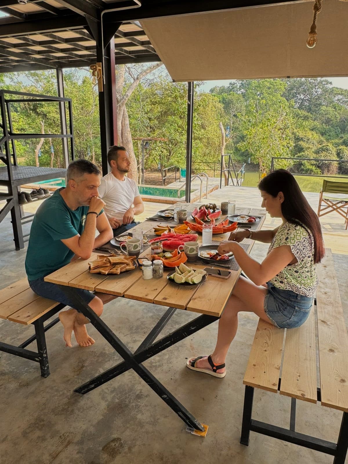 A group of guests eating together at a long table under the open roof